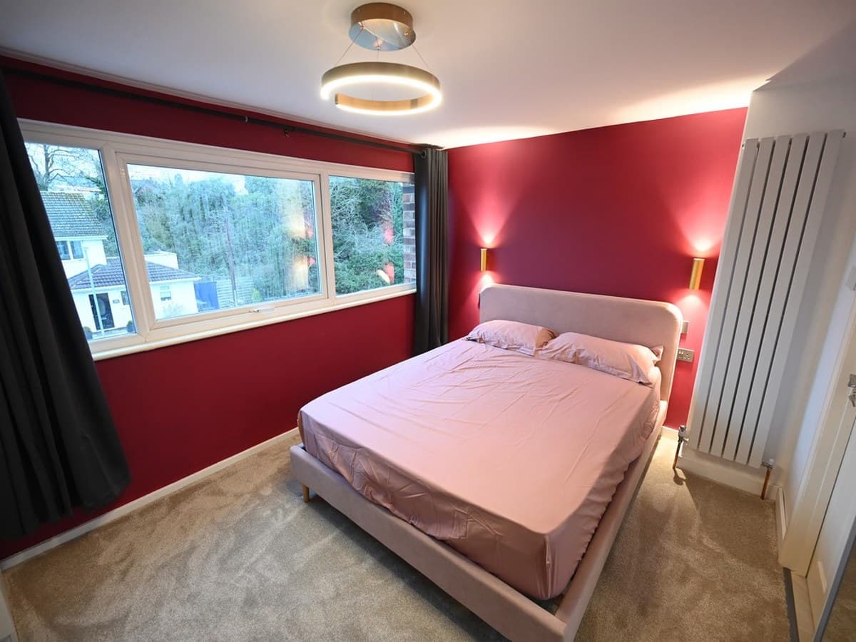 Main bedroom — oxblood wall, paired wall lights