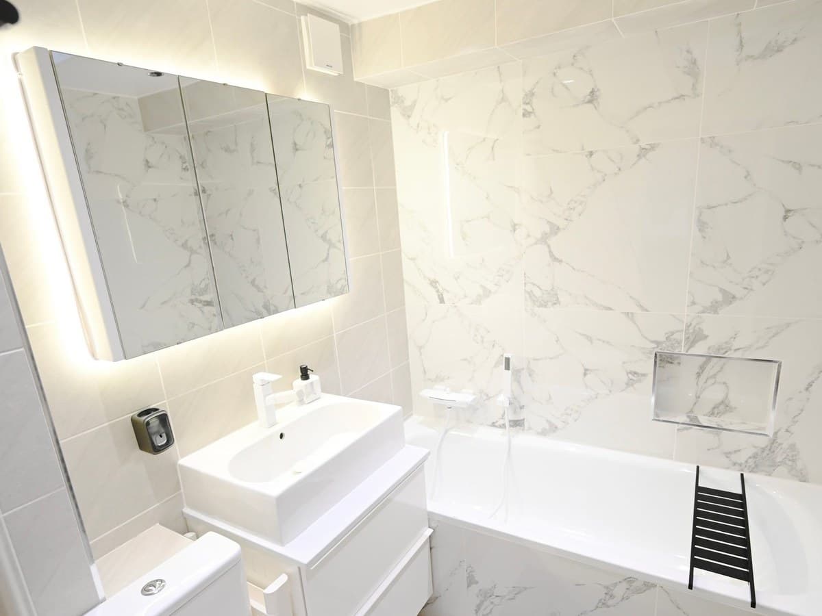 Bathroom — marble-effect boards, inset bath, mirror cabinet